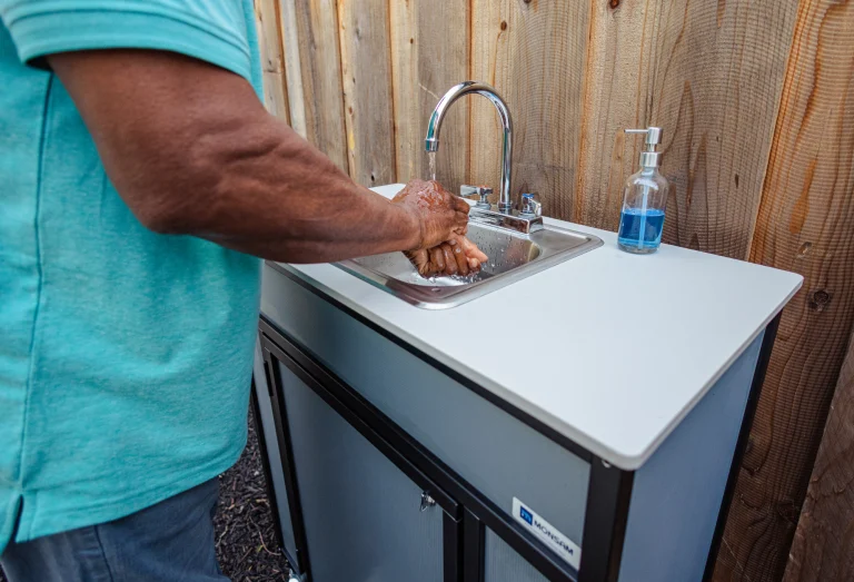 Handwashing outside in Monsam portable sink. No plumbing.